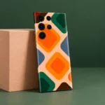 Abstract mobile skin with orange and green rounded diamonds on peach, studio angle
