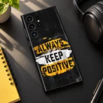 Always Keep Positive quote mobile skin in black, yellow and white, sunlit desk flat lay view