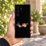 Flying Hanuman black mobile skin held in a leafy sunlit courtyard