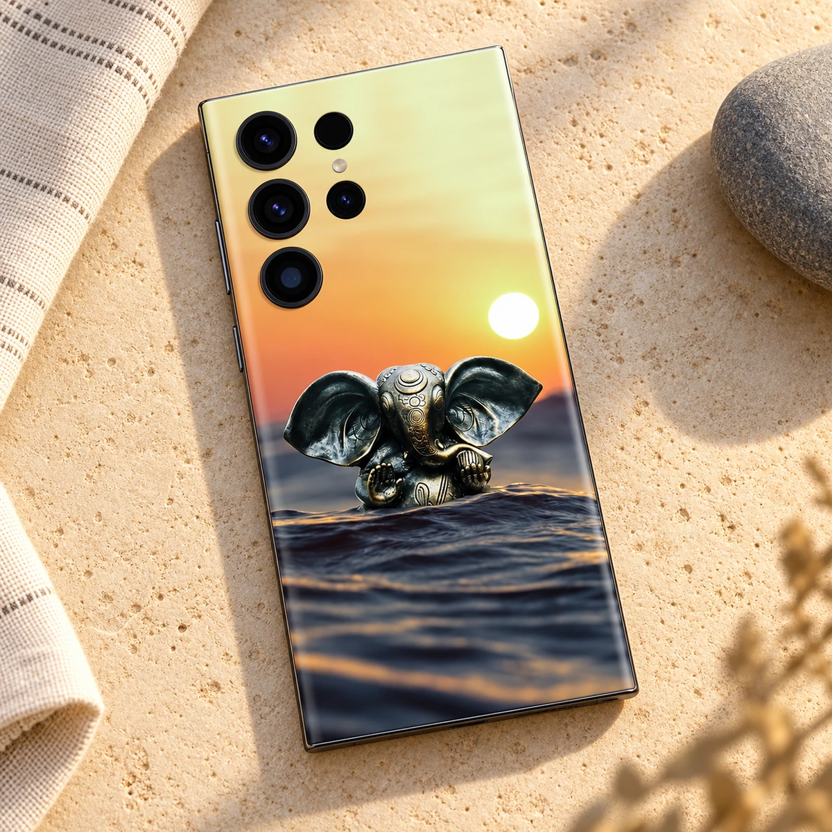 Lord Ganpati Sunset Water Mobile Skin – sandstone flat lay Lord Ganpati sunset water mobile skin with bronze Ganesha idol – sandstone flat lay