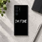 Black I'm Fine mobile skin with white distressed lettering, concrete flat lay