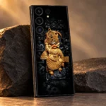 Close detail of ornate golden Kashtabhanjan Hanuman idol artwork on black mobile skin