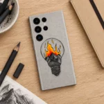 Grey mobile skin with a hand-drawn light bulb containing mountains and orange-yellow illustrated flames, sketch desk flat lay