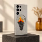 Grey mobile skin with a hand-drawn light bulb containing mountains and orange-yellow illustrated flames, charcoal studio angle