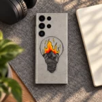 Grey mobile skin with a hand-drawn light bulb containing mountains and orange-yellow illustrated flames, felt workspace lifestyle