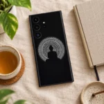 Black Buddha mandala mobile skin on linen beside a notebook and tea