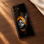 Black Lord Krishna mobile skin with saffron turban and peacock feather on walnut wood