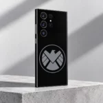 Black Marvel Shield mobile skin with grey circular eagle emblem, concrete studio angle