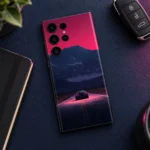 Night Journey mobile skin with a car on a pink-lit road beneath navy mountains, navy desk flatlay
