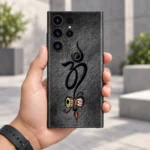 Om With Damru mobile skin with black Om and colourful damru on charcoal - in-hand lifestyle