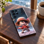 One Piece mobile skin with laughing chibi Luffy in a straw hat, cafe tabletop view
