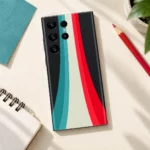 Abstract Design Mobile Skin with teal, ivory and red stripes in artist desk flat lay view