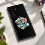 Black Rubik's Cube mobile skin with colorful illustrated cube artwork, creative desk flat lay