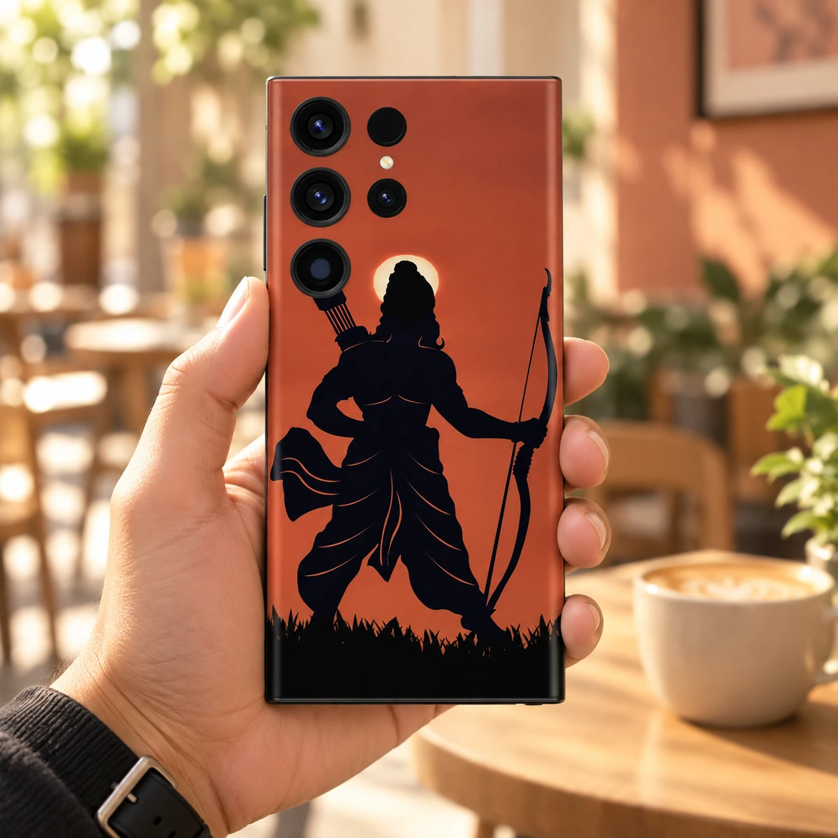 Shree Ram Rust Orange Archer Mobile Skin - Cafe in-hand Shree Ram rust orange archer mobile skin held in a sunlit cafe