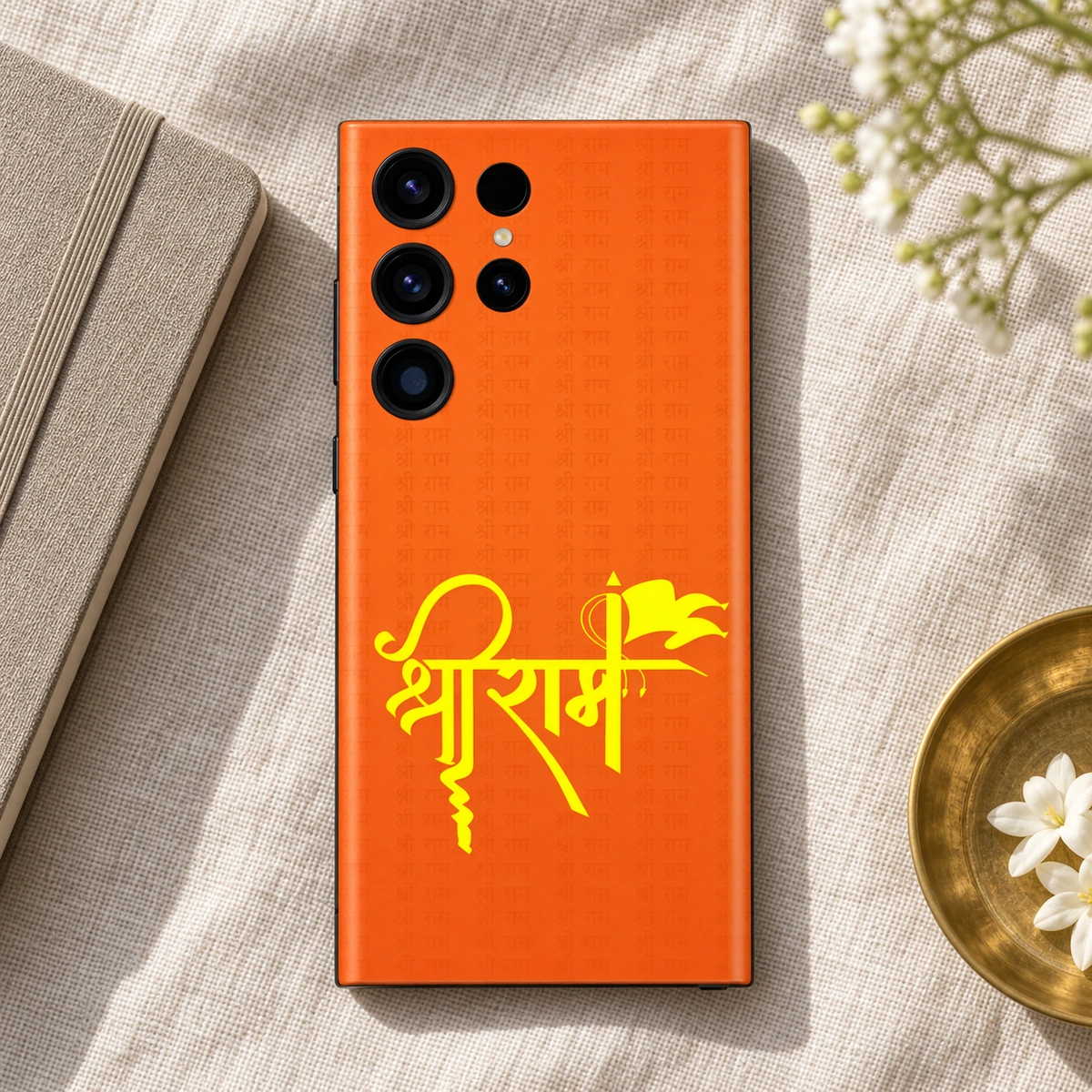 Shree Ram Saffron Yellow Calligraphy Mobile Skin - Linen flatlay Shree Ram calligraphy mobile skin on linen beside a notebook and brass dish