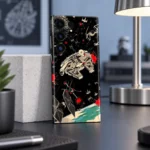 Star Wars mobile skin with Millennium Falcon and TIE fighter artwork on black, daylight workspace angle