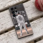 Virat Kohli mobile skin showing VIRAT 18 on a white Test jersey, cricket bench flat lay