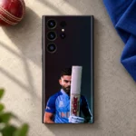 Virat Kohli mobile skin showing his blue-jersey portrait behind an upright bat, cricket desk flat lay