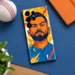 Virat Kohli illustrated mobile skin in orange and blue, blue desk flat lay