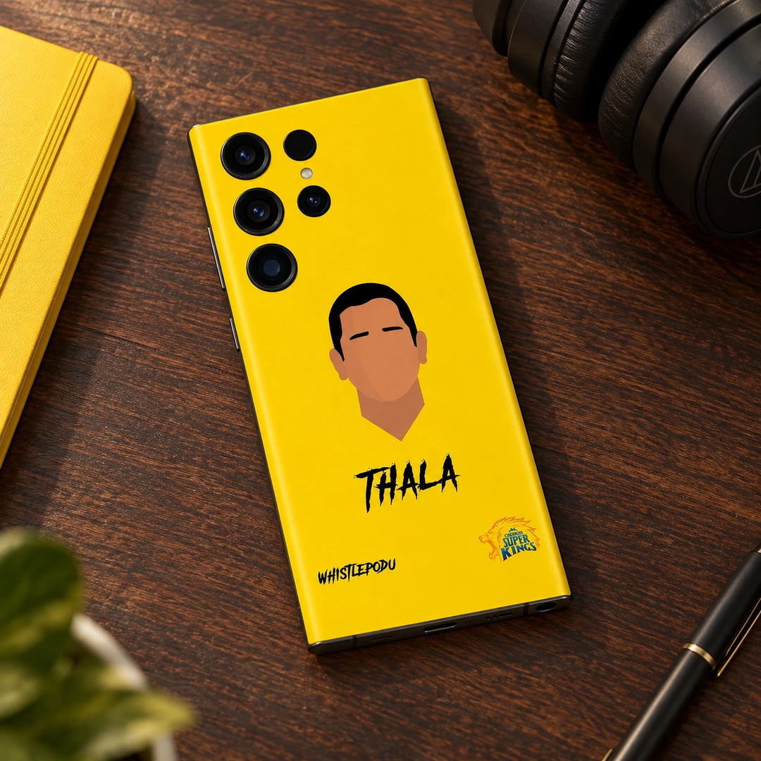 Dhoni Thala Yellow Mobile Skin - Desk lifestyle Yellow Dhoni Thala mobile skin lying on a wooden desk beside headphones and a yellow notebook