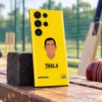 Yellow Dhoni Thala mobile skin standing on a wooden bench near cricket practice nets