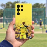 Yellow Dhoni photo mobile skin with wicketkeeping gloves, handheld cricket ground view