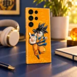 Goku peace sign mobile skin on a golden orange background, navy desk angle