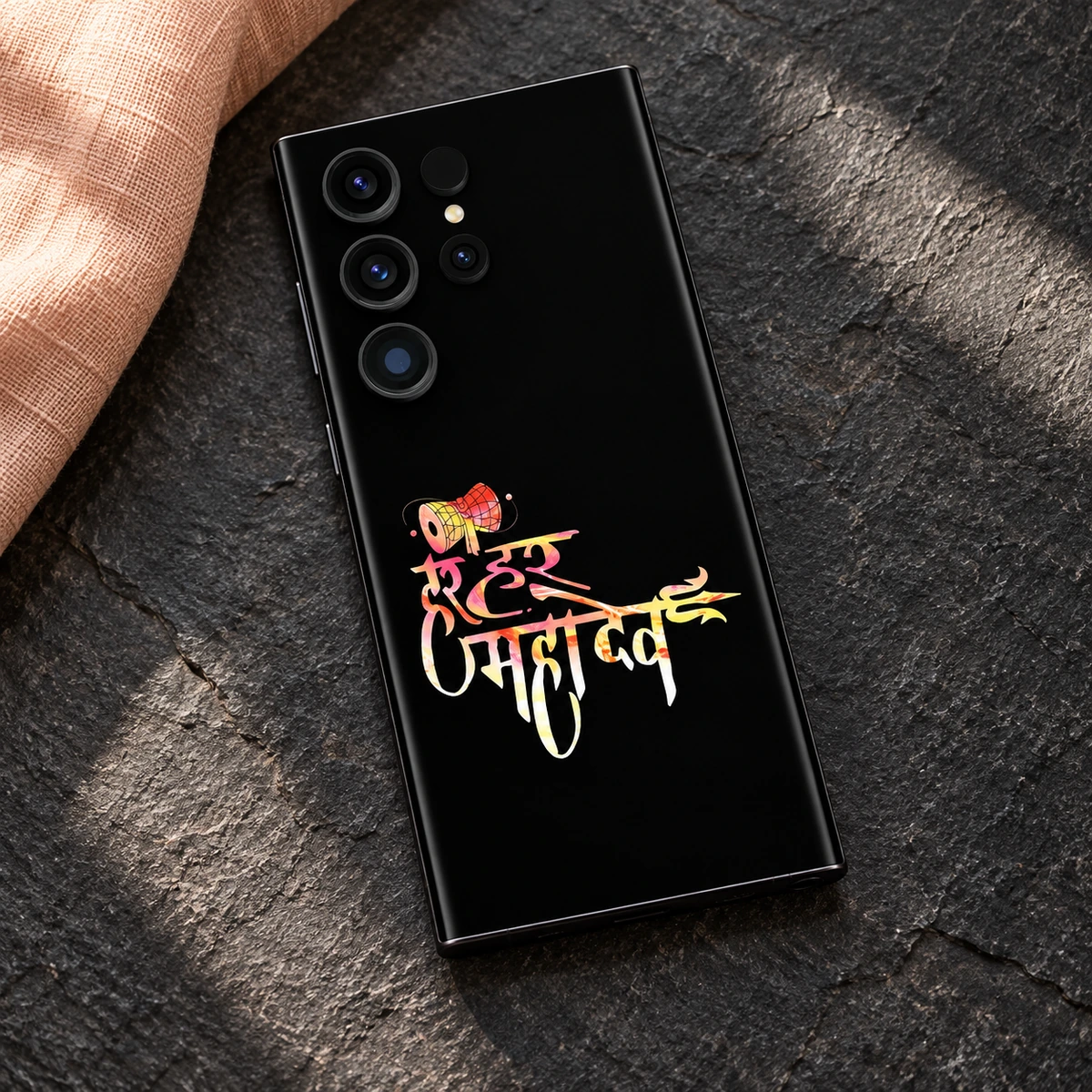 Har Har Mahadev Colourful Damru Mobile Skin - Linen Flatlay Colourful Mahadev calligraphy mobile skin styled on slate with peach linen
