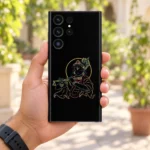 Krishna outline halo mobile skin held in a leafy sunlit courtyard