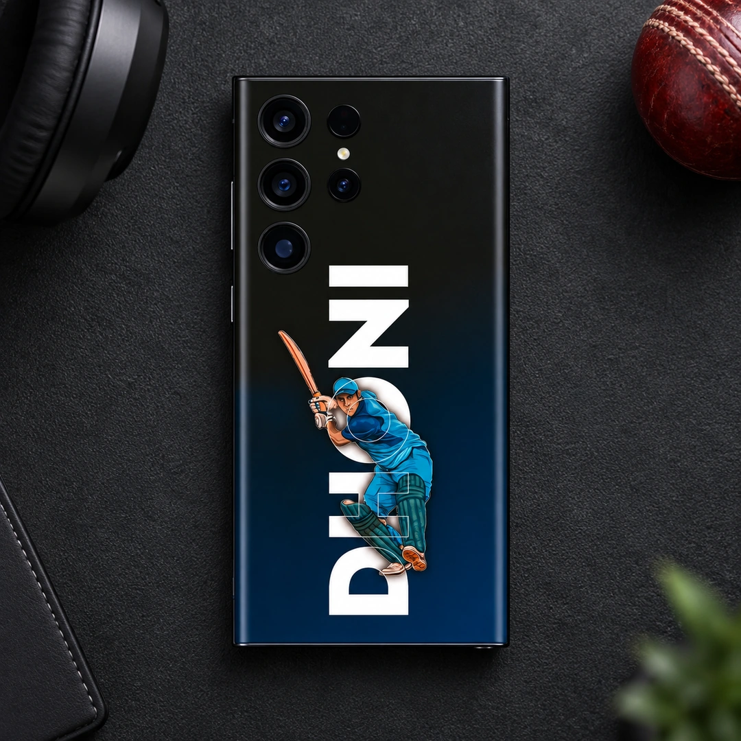 MS Dhoni Batting Mobile Skin – Dark desk flat lay MS Dhoni mobile skin with blue batting illustration and vertical DHONI lettering, dark desk flat lay