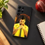 MS Dhoni photo mobile skin with yellow jersey portrait and orange lion artwork, cricket desk flat lay