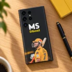 Black and yellow MS Dhoni mobile skin on a wooden desk