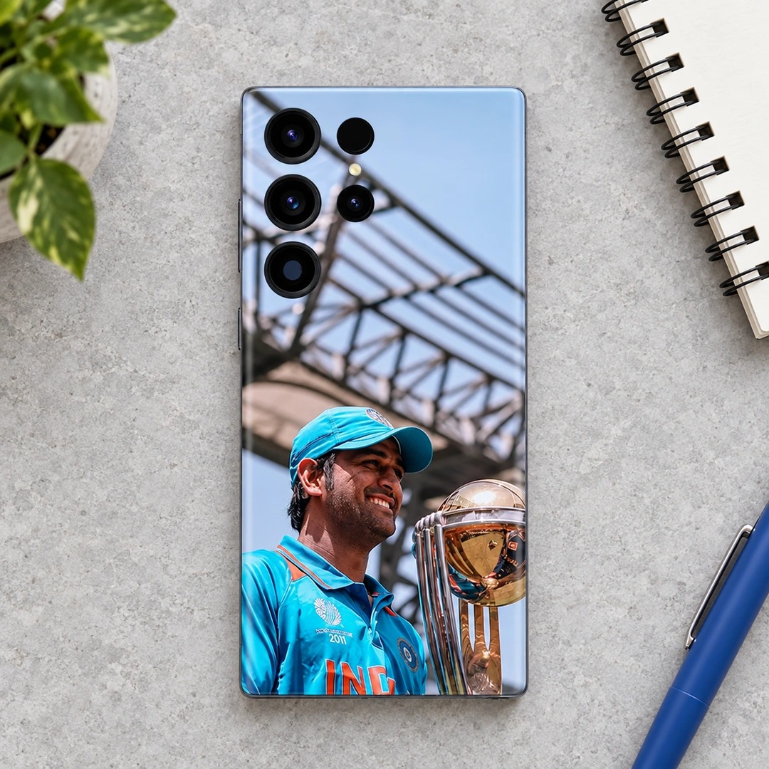 MS Dhoni Trophy Photo Mobile Skin – Daylight desk flat lay MS Dhoni trophy photo mobile skin with blue jersey and cap, daylight desk flat lay