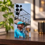 MS Dhoni trophy photo mobile skin with blue jersey and cap, warm wooden shelf display