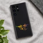 Radhe Radhe mobile skin with gradient Hindi calligraphy on charcoal black, linen flat lay