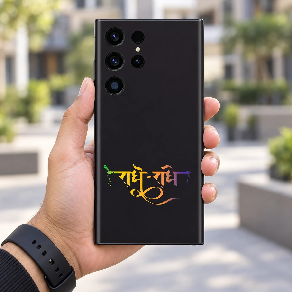 Radhe Radhe Gradient Calligraphy Mobile Skin - In-hand lifestyle Radhe Radhe mobile skin with gradient Hindi calligraphy on charcoal black, in-hand lifestyle