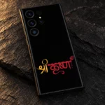 Close view of golden Shree and red Krishna lettering with a peacock feather accent