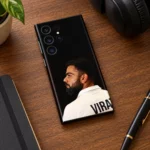 Virat Kohli black portrait mobile skin lying on a walnut desk beside headphones