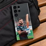 Virat Kohli photo mobile skin showing bat portrait in black-and-red cricket jersey, black sports bag