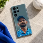 Virat Kohli blue cap portrait mobile skin lying on pale stone beside a white cricket ball