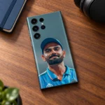Virat Kohli blue cap portrait mobile skin lying on a walnut desk beside headphones and a blue notebook
