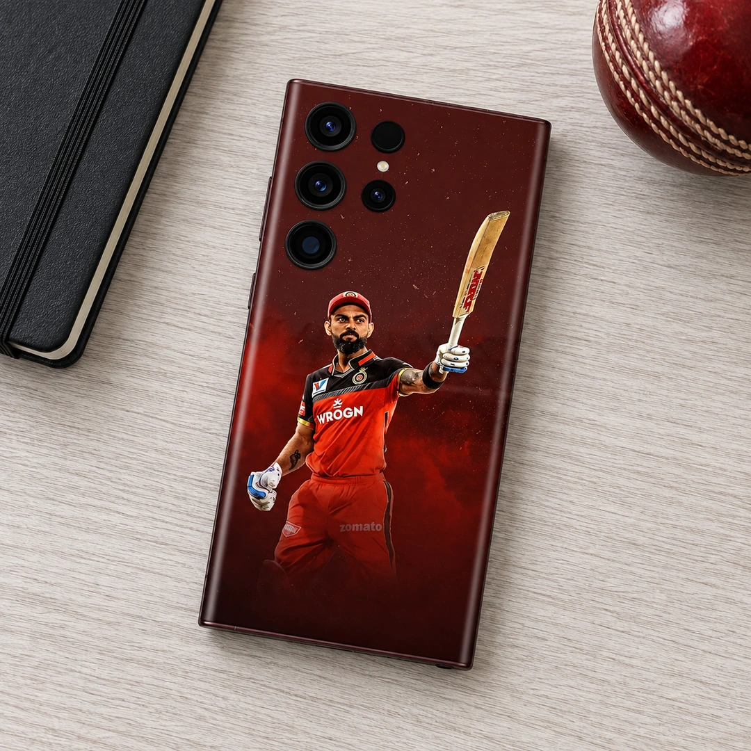 Virat Kohli Red Kit Mobile Skin - cricket desk flat lay Virat Kohli mobile skin with raised bat and red cricket kit against burgundy, cricket desk flat lay