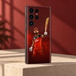 Virat Kohli mobile skin with raised bat and red cricket kit against burgundy, red studio angle