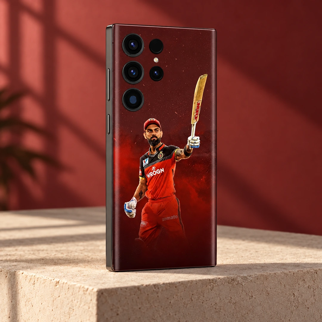 Virat Kohli Red Kit Mobile Skin - red studio angle Virat Kohli mobile skin with raised bat and red cricket kit against burgundy, red studio angle