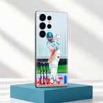 Virat Kohli batting in white Test uniform on a mobile skin, teal studio pedestal view