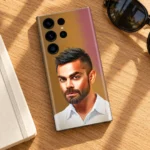 Virat Kohli illustrated portrait mobile skin with white shirt and warm brown background, oak desk flat lay