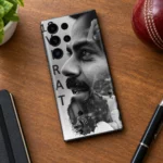 Virat Kohli black and white collage mobile skin on a wooden desk beside a cricket ball