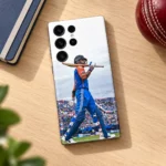 Virat Kohli mobile skin with blue kit and bat across shoulders, oak desk flat lay