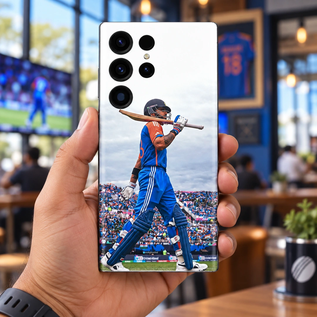 Virat Kohli Bat-on-Shoulder Mobile Skin – Handheld cafe view Virat Kohli mobile skin with blue kit and bat across shoulders, handheld cafe view