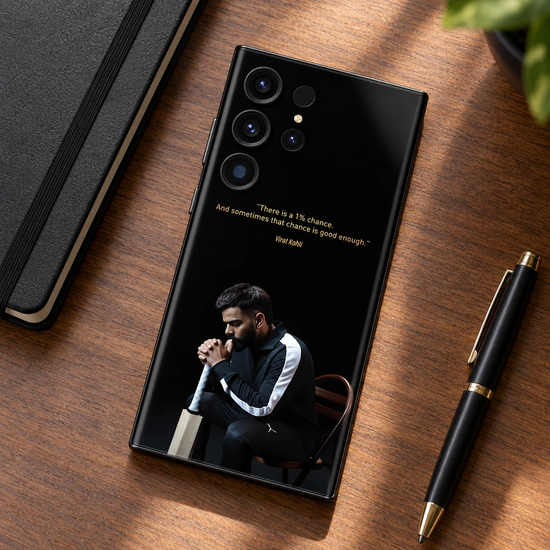 Virat Kohli 1% Chance Quote Mobile Skin - Walnut Desk Flat Lay Black Virat Kohli mobile skin with gold 1% chance quote and seated portrait, walnut desk flat lay